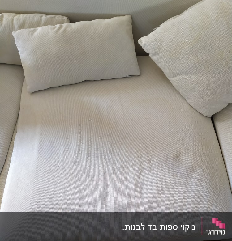 ספה בהירה עם כריות, כתמים קלים על המושב